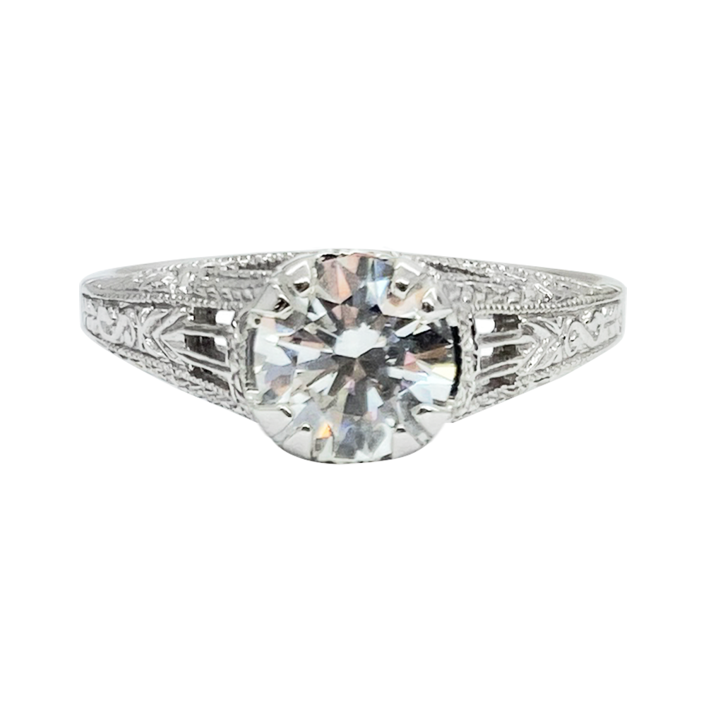 Silver diamond engagement ring with a large center stone and intricate filigree detailing on the band.